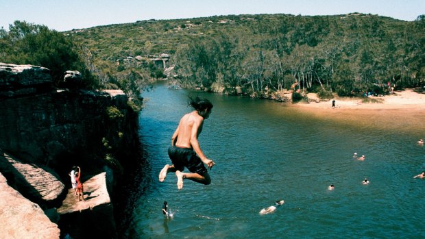 Kids jumping off rocks into Wattamolla lagoon.