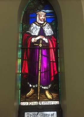 Stained glass window of King Arthur inside a church.