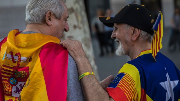 Two men, one wearing a Spanish flag, left, and the other wearing an estelada' or independence flag, talk during the celebration of a holiday known as "Dia de la Hispanidad" or Spain's National Day, in Barcelona.