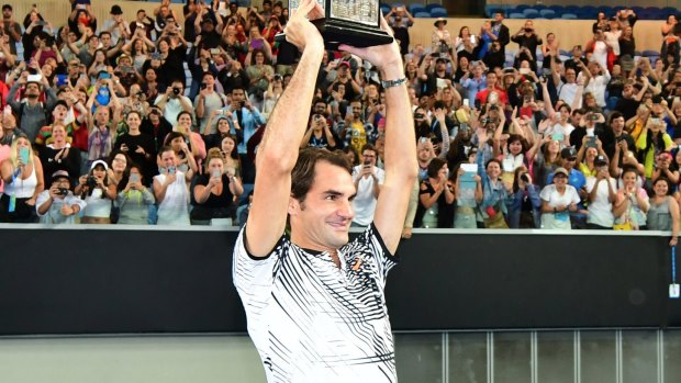 Man of the people: Roger Federer presents the trophy to fans on Margaret Court Arena.