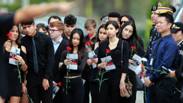 Mourners hold flowers during the funeral for Peter Wang.