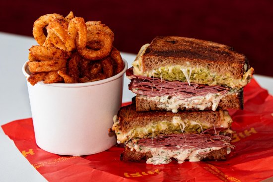 The menu is focused on sandwiches (Reuben pictured), curly fries, shakes and coffee.