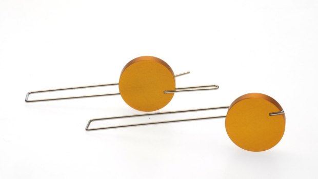 Off-centre earrings by Phoebe Porter made from yellow aluminium and stainless steel.