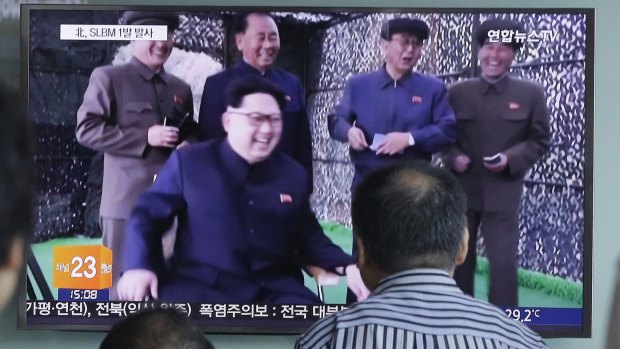 People in South Korea watch a TV news program showing North Korean leader Kim Jong-un.