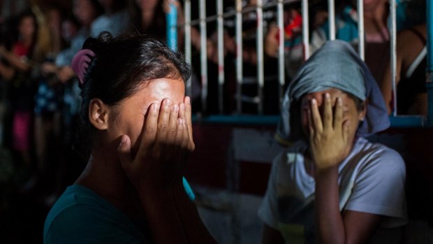 Two women await the fate of their loved ones during an alleged police drug raid on a suspected drug den in Manila. 