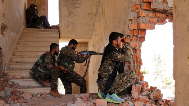 Kurdish People's Protection Units (YPG) fighters take up positions inside a damaged building in al-Vilat al-Homor neighborhood in Hasaka city in July 2015.