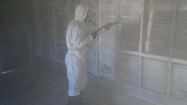 A cleaner decontaminating a garage with chemical foam.