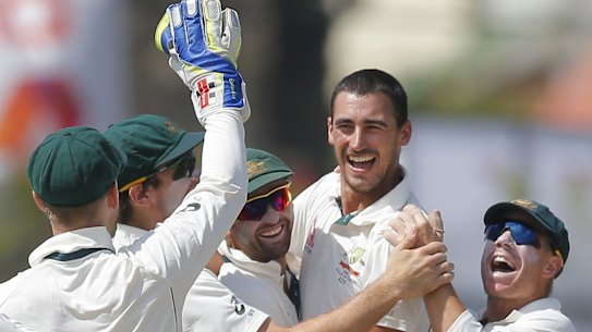 Australia's Mitchell Starc celebrates with teammates after taking a wicket with the first ball.