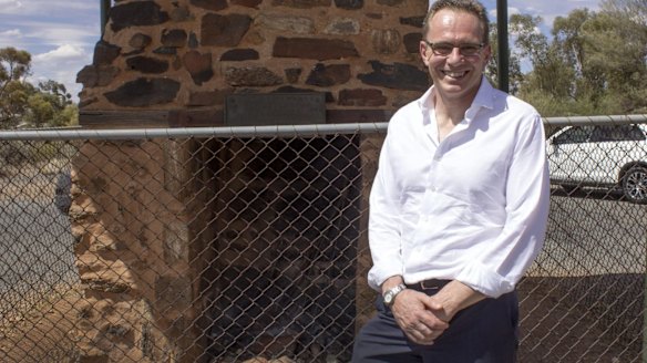 Andrew Mackenzie standing in front of stone chimney that marks the site of the hut built by BHP in May 1885 to house its first manager William Jamieson.