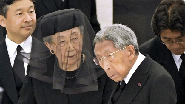 Prince Mikasa, right, with his wife Princess Yuriko, centre, and Crown Prince Naruhito, left, attends Prince Katsura's funeral service at Toshimagaoka graveyard in Tokyo in 2014.