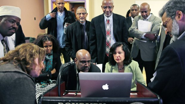 Muslim, Christian, minority and government leaders fix their eyes on a laptop screen showing a video as part of a federal pilot program called Countering Violent Extremism, at Roxbury Community College in Boston. 