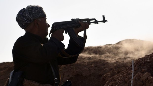 A Kurdish peshmerga soldier fires at an Islamic State position during an assault to recapture the village of Tiskharab.