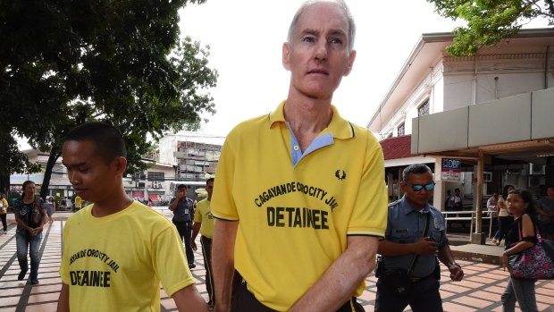 Peter Scully (right) arrives at the Cagayan De Oro court handcuffed to another inmate on his first day of his trial. 