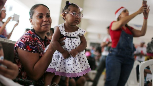 Ana Livia, centre, who was born with microcephaly, is held by her mother Janaina during a Christmas party in support of children with deficiencies, in Recife, Brazil. 