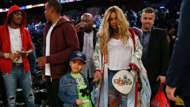 Beyonce holds the hand of her daughter Blue Ivy Carter, while her husband, rapper Jay-Z, talks in the background, after the NBA All-Star basketball game in New Orleans.