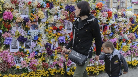Passersby contemplate a wall of artificial flowers set up by the US-based Wall of Flowers Foundation in memory of the victims of Russia's invasion, in Ukraine's western city of Lviv, Ukraine, Monday, April 25, 2022. (AP Photo/Mykola Tys)