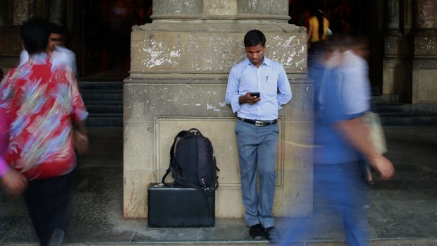 A man surfs the internet on his smartphone outside a railway station in Mumbai on Tuesday. 