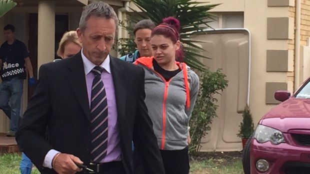 A woman is led away by Armed Crime Taskforce Detective Inspector Steve Clark after a raid in Point Cook.