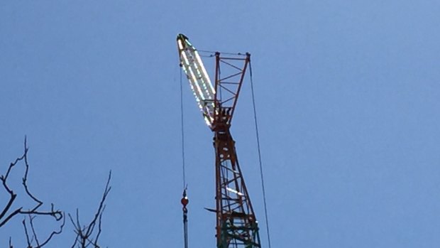 Police are asking people to avoid the area as they negotiate with a man who has climbed a large crane on a construction site.