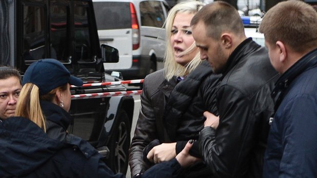 Maria Maksakova is assisted from the place where her husband Denis Voronenkov was killed.