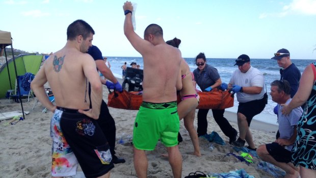 A teenager girl is lifted from the beach after losing part of her arm in the shark attack. 
