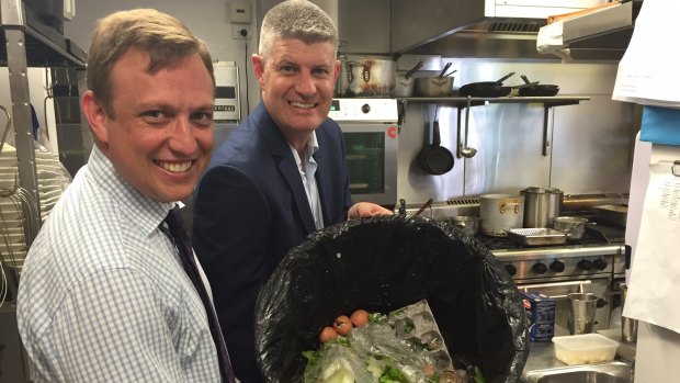 Environment Minister Steven Miles helps Commonwealth Games Minister Stirling Hinchliffe measure wasted food on the Gold Coast.
