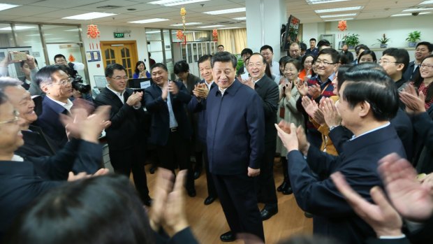 Workers applaud as Chinese President Xi Jinping talks with staff at the <i>People's Daily</i> in February.