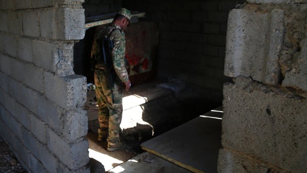 A Peshmerga fighter looks into an underground tunnel built by Islamic State fighters in Badana, east of Mosul. IS built tunnels under residential areas so they could move without being seen from above.