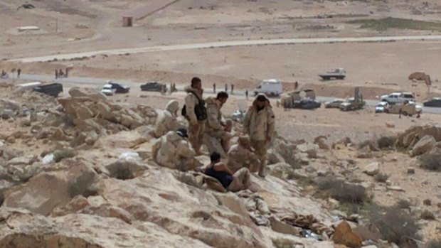 Syrian government soldiers gather on a hill at the entrance of Palmyra on Thursday. 