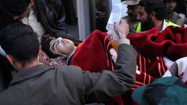 Medical support: Pakistani men transport a wounded student to hospital after Taliban gunmen attacked the school in Peshawar. This is not the boy Salman who played dead to avoid the gunmen.