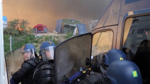 Police attend the scene after huts were set on fire during clashes between migrants at a makeshift camp in Calais last week.