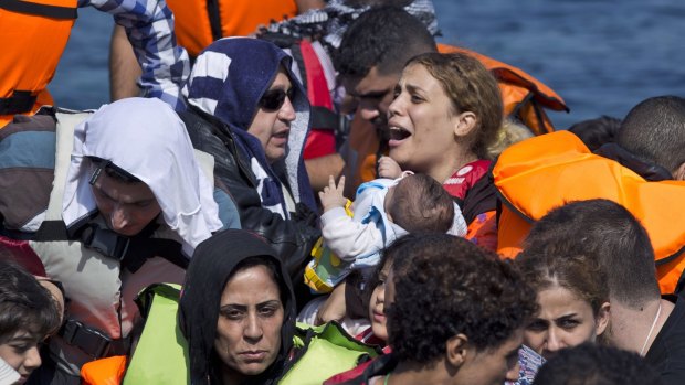 Syrian refugees arrive aboard a dinghy after crossing from Turkey to the Greek island of Lesbos on September 20.