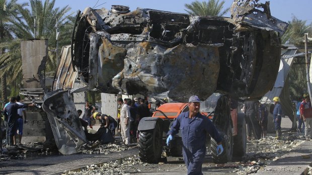 Municipality workers remove destroyed vehicles at the scene of a deadly suicide bomb attack in Hillah, south of Baghdad, on Sunday, March 6, 2016. 