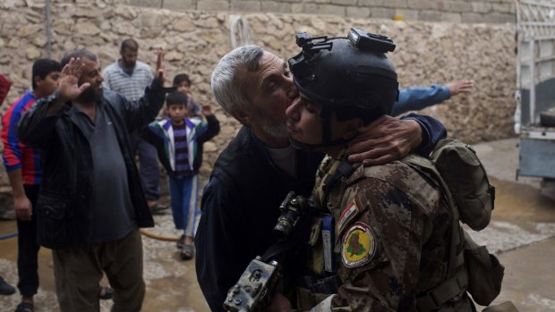 A man kisses an Iraqi soldier in eastern Mosul, Iraq.