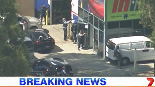 Police draw their firearms outside Inline Signs, following a shooting at the premises.