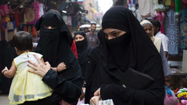 Indian Muslim women walk at a market area in Delhi, India.