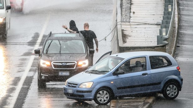 Motorists who had stopped to assist a driver who had lost control and mounted a kerb urge oncoming vehicles to avoid a flooded section of Parkes Way.