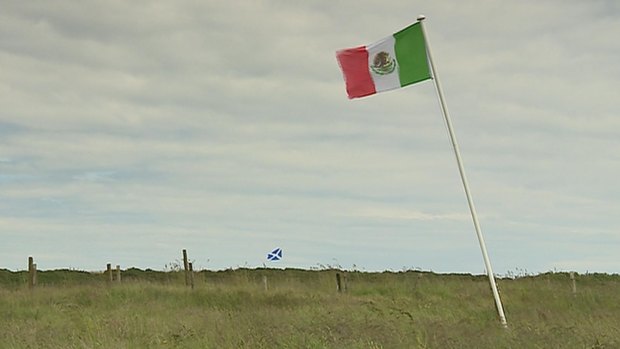 The Mexican flag, foreground, and the Scottish flag blow on land owned by David Milne, one of Donald Trump's long-standing opponents, near the Turnberry golf course.