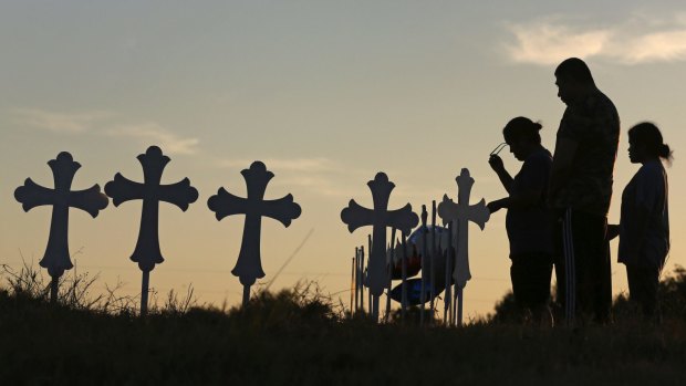Irene and Kenneth Hernandez and their daughter Miranda Hernandez say a prayer on Monday, in front of some of the crosses placed in a field in Sutherland Springs.