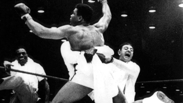 In this Feb. 25, 1964, file photo with flailing arms and legs, new heavyweight boxing champion Cassius Clay is lifted off the ring floor in Miami Beach by one of his handlers when Sonny Liston was unable the answer the bell for the seventh round. 