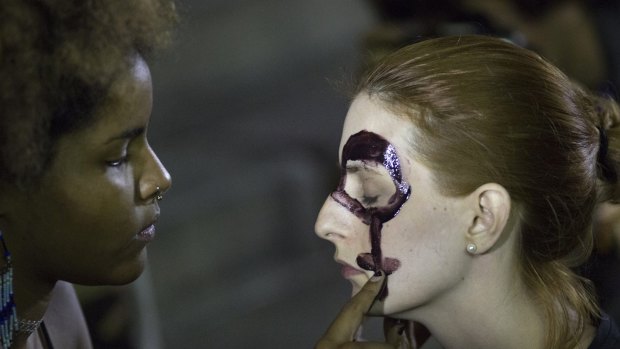 Women paint their faces with female gender symbols to against the gang rape of a 16-year-old girl in Rio.