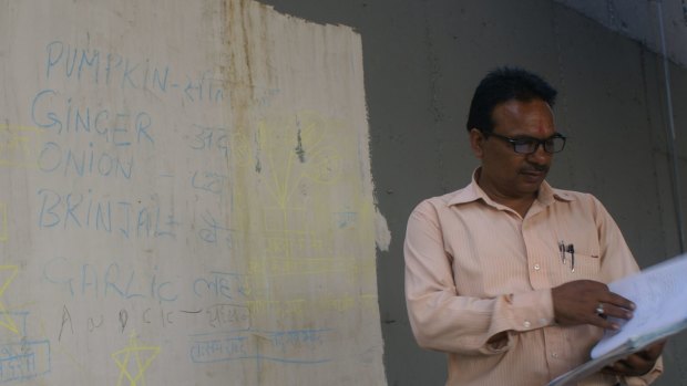 Rajesh Kumar Sharma, himself denied an education, teaches the children the English and Hindi names of common vegetables on a "whiteboard" painted on the rail bridge's wall.