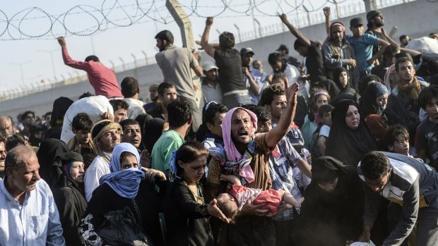 Syrians pass through broken border fences to enter Turkish territory near the border crossing at Akcakale on Sunday.