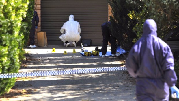 Forensic investigators process evidence in the driveway of the Wanniassa home where Neal Wilkinson was murdered.
