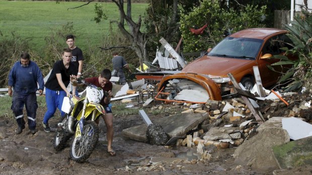 A motorbike is retrieved from the flood detritus.