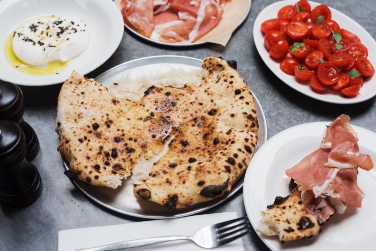 Wood-fired bread with three antipasti plates - prosciutto, burrata and tomato - at Totti's at the Royal Hotel in Bondi.