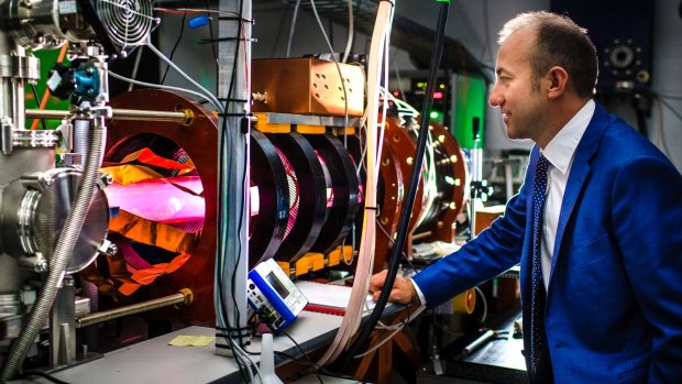 Director of the Australian Plasma Fusion Research Facility at ANU Dr Cormac Corr with the glowing MAGPIE II - a machine used to test plasma interactions. 