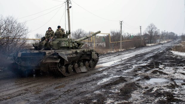 A Ukrainian tank rolls past a damaged vehicle about five kilometres from the Donetsk airport on Monday.