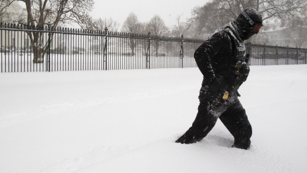 A uniformed US Secret Service police officer stands guard in a knee-deep snow outside the White House in Washington.