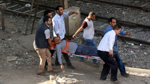Wounded: Egyptian men carry an injured man on a stretcher after the bomb exploded on the metro.